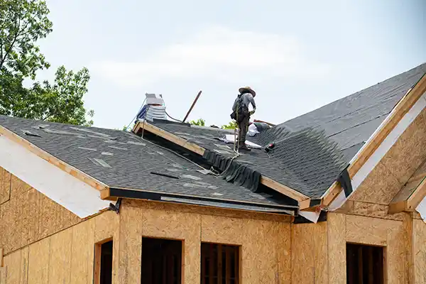 Roofer installing shingles on a new home